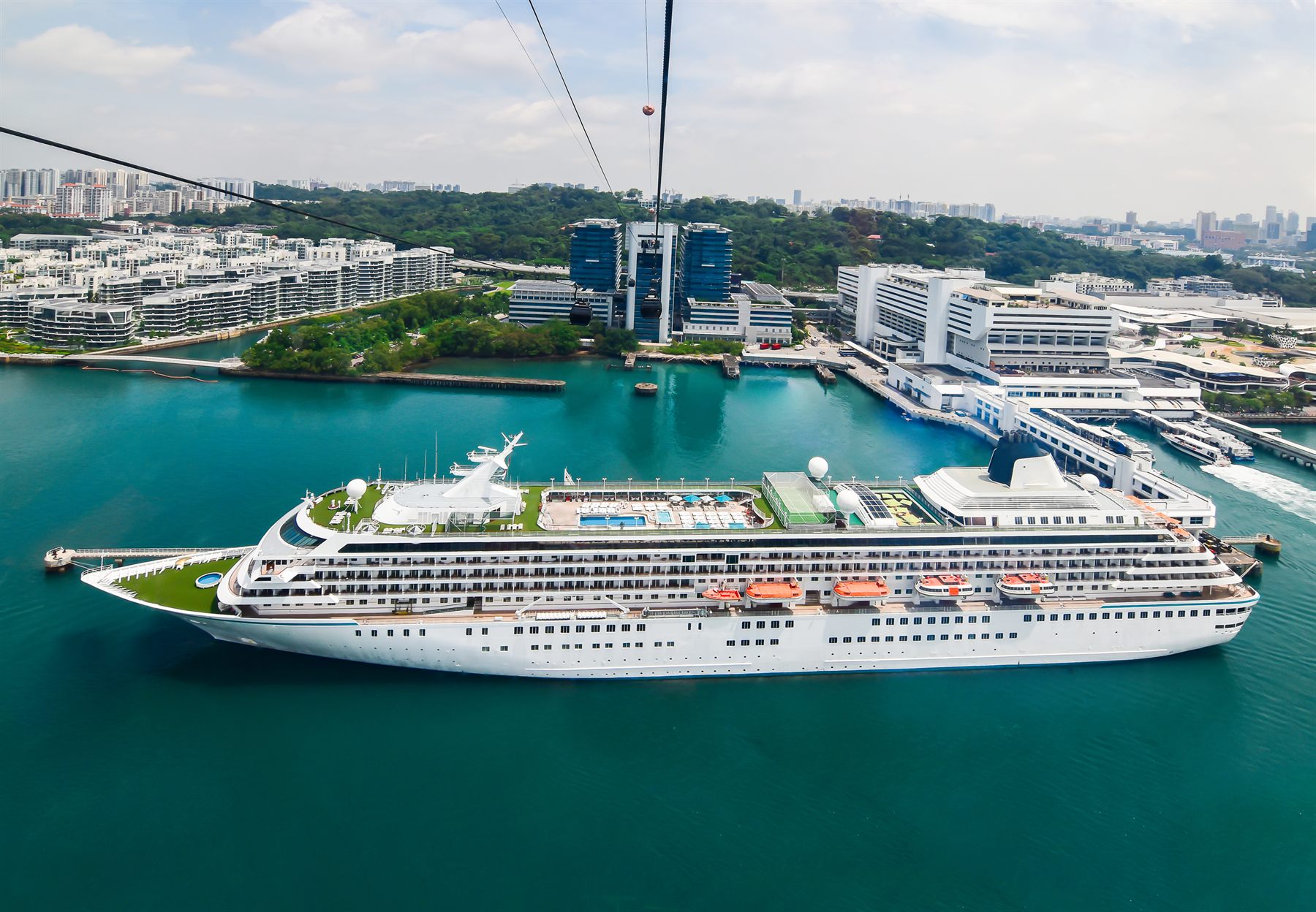 A cruise ship berthed in Singapore beneath a harbor cable car
