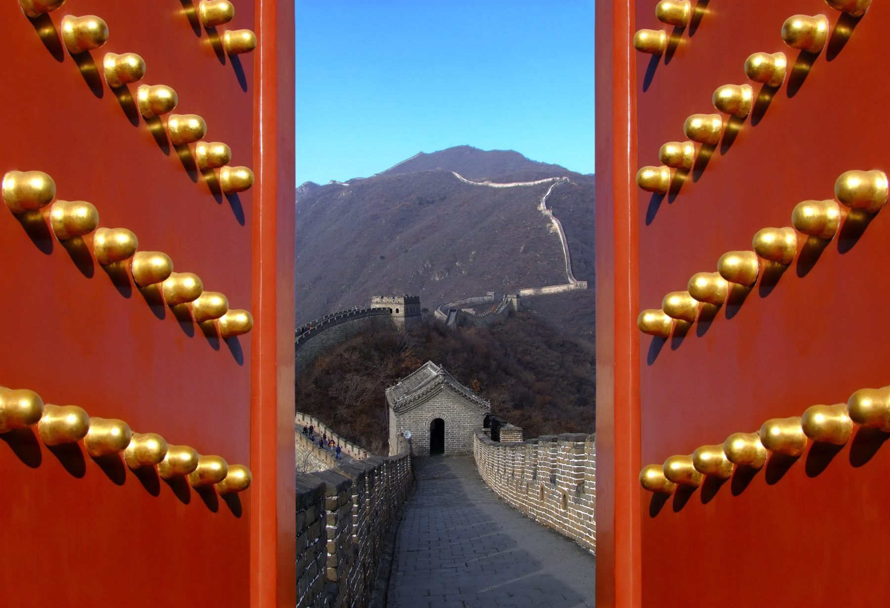The Great Wall of China seen through a pair of red studded doors